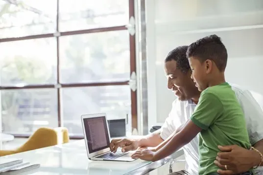 man and child looking at computer
